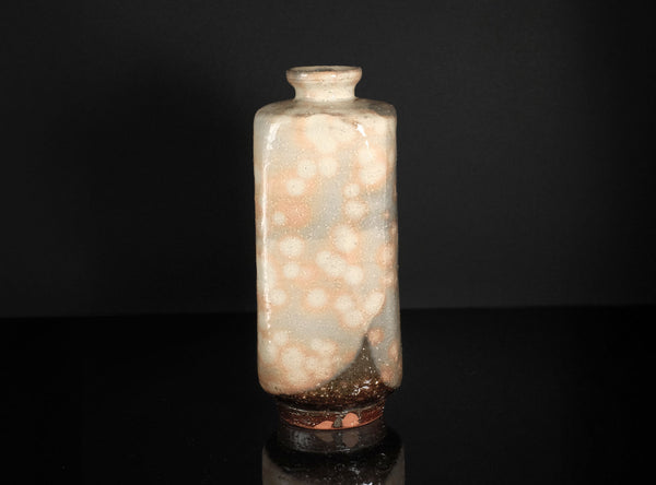 Decorative glass bottle with a textured surface on a black background