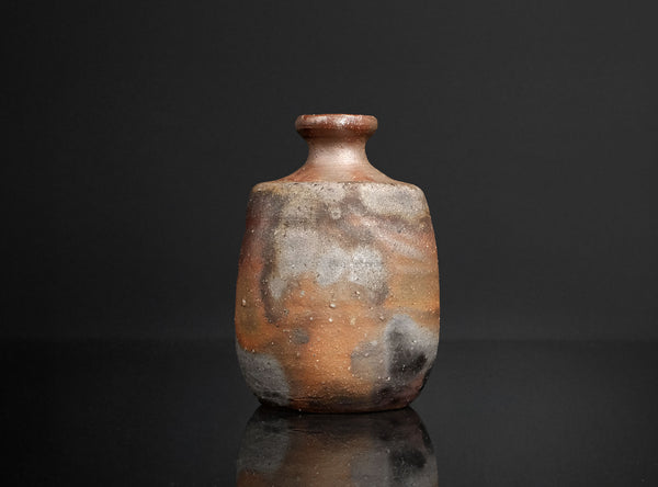 Small ceramic bottle with a textured surface on a black background