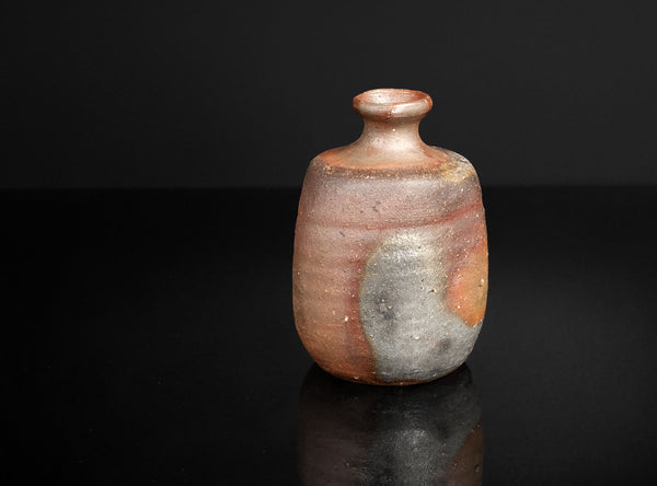 Small ceramic bottle with a textured surface on a black background