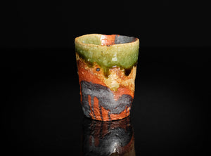 Decorative ceramic cup with multicolored glaze on a black background
