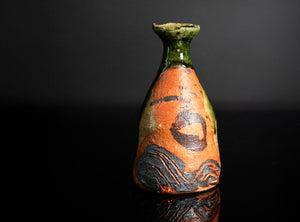 Decorative ceramic vase with orange and green glaze on a black background
