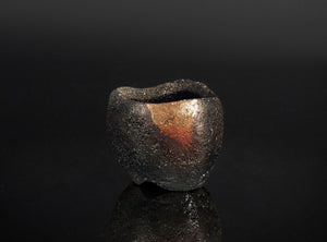 Black ceramic bowl with metallic sheen on a black background