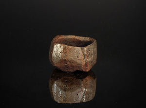 Brown ceramic cup on a black reflective surface