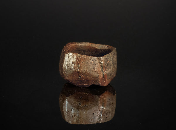 Brown ceramic cup on a black reflective surface