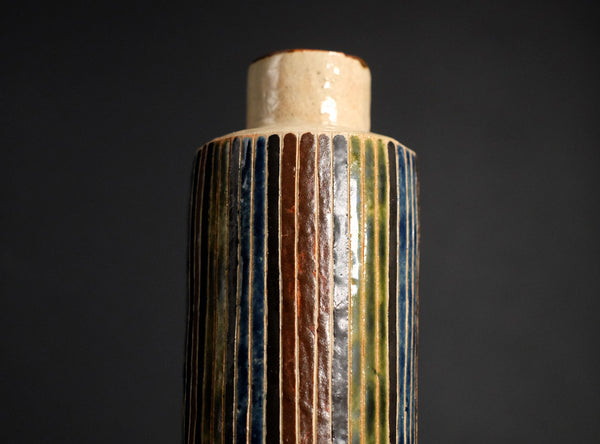 Cylindrical object with ribbed texture on a dark background