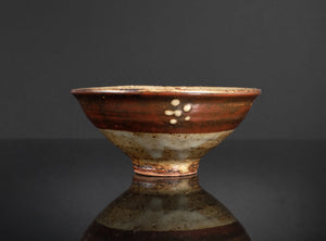 Ceramic bowl with brown and white glaze on a dark background