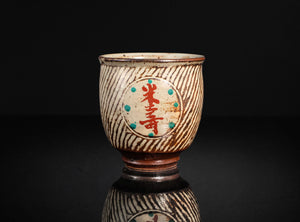 Ceramic cup with decorative patterns and text on a black background