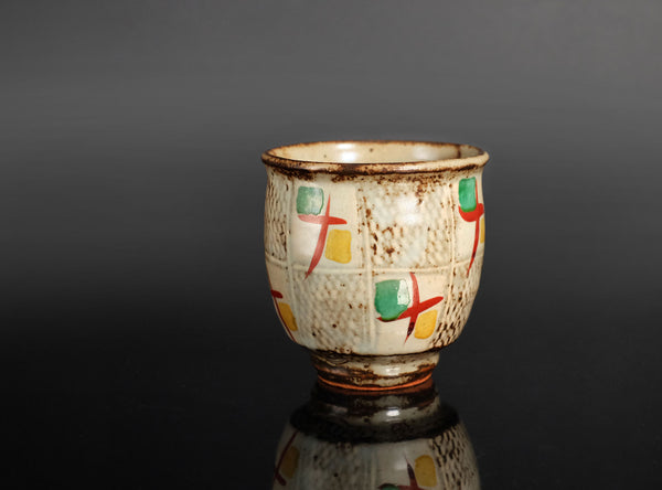 Ceramic cup with abstract designs on a reflective surface