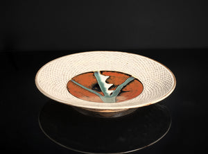 Ceramic dish with textured surface and abstract design on a black background
