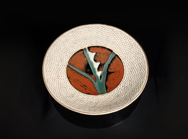 Ceramic plate with a textured rim and central design on a black background