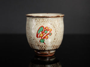 Ceramic cup with textured surface and colorful design on a dark background