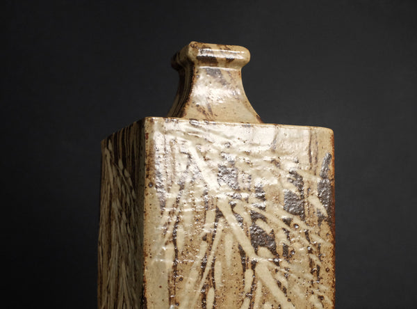 Ceramic square vase with textured surface on a dark background