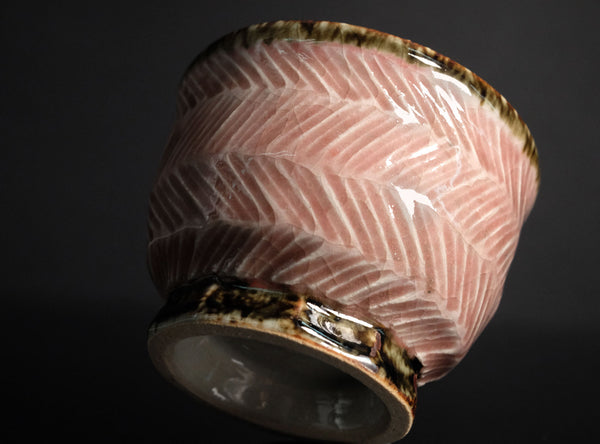 A rounded copper-red tea cup from Tatsuzo Shimaoka’s Mashiko practice, enlivened by pale cord patterns across a softly coloured pink ground. Its lower, broader proportions give it a generous open profile, offering a distinct counterpart to the taller cup with which it was originally paired.

The body curves inward beneath the wide mouth, then rounds towards a short, clearly defined circular foot. A lightly flaring rim frames the pale glazed interior. The changing contours give the cup a comfortable visual b