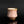 Load image into Gallery viewer, A pink ceramic tea cup with a white hand-painted herringbone pattern and a metallic gold-brown rim, set against a dark reflective background.
