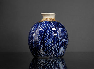 Blue ceramic vase with white patterns on a dark gray background