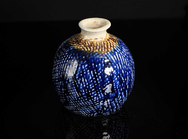 Decorative ceramic vase with blue glaze and gold accents on a black background