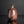 Load image into Gallery viewer, A rustic handmade ceramic bottle with a rounded body, short neck, and a glossy reddish-brown glaze with dark patches, set against a dark gray background with a reflection below.
