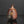 Load image into Gallery viewer, A rustic handmade ceramic bottle with a rounded body, short neck, and a glossy reddish-brown glaze with dark patches, set against a dark gray background with a reflection below.

