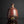 Load image into Gallery viewer, A rustic handmade ceramic bottle with a rounded body, short neck, and a glossy reddish-brown glaze with dark patches, set against a dark gray background with a reflection below.

