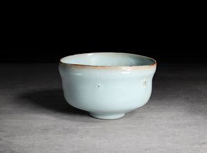 Ceramic cup with a light blue glaze on a gray background