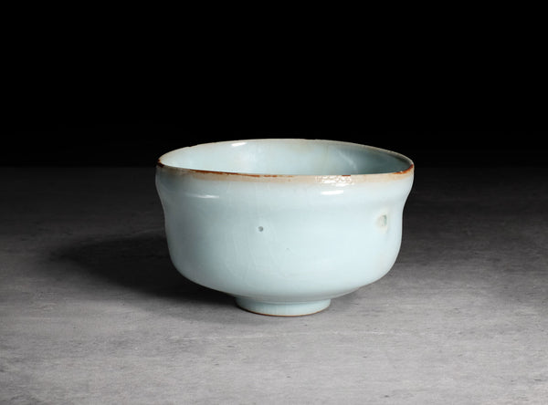 Ceramic cup with a light blue glaze on a gray background