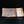 Load image into Gallery viewer, A rectangular ceramic plate with a textured orange-brown glaze, featuring a vertical band of white speckled glaze, a tan bamboo motif, and a small yellow accent, displayed on a reflective black surface.
