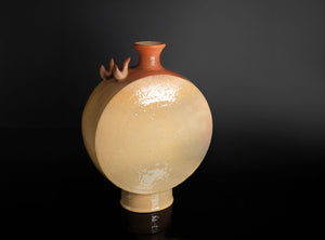 A ceramic vase with a rounded bulbous body, a narrow reddish-orange neck, and three small decorative protrusions near the top, shown on a dark black background.