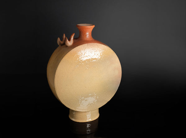 A ceramic vase with a rounded bulbous body, a narrow reddish-orange neck, and three small decorative protrusions near the top, shown on a dark black background.