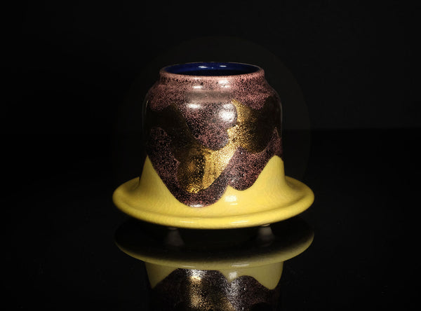 Ceramic container with purple and gold design on a black background