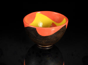 Ceramic bowl with orange and yellow interior on a black background