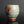 將圖片載入到圖庫檢視器中， A handmade ceramic tea cup with a textured, ribbed surface and small shell inlays, featuring a green glaze with reddish-brown accents, displayed on a dark reflective surface.
