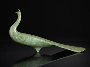 Green jade peacock sculpture on a reflective surface with a black background