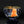 Load image into Gallery viewer, A clear glass bowl with a textured, ribbed exterior and a metallic gold interior, featuring a prominent orange inlay or reflection on the front, set against a dark reflective background.
